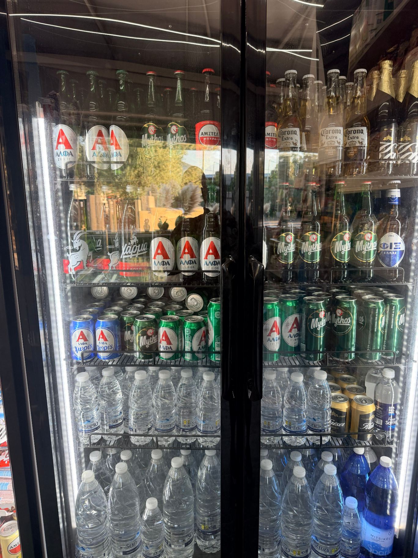 Fridge full of cold beers Mythos Alfa Corona and Cretan Samaria water at AMOS SEASIDE Mini Market Marathi Chania